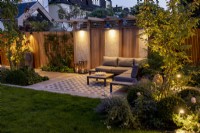 Jardin moderne avec terrasse et pergola la nuit avec éclairage