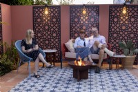 Détente en famille autour d'un foyer dans leur patio de jardin de style marocain