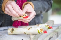 Femme fixant les ovales en bois minces et les grains de poivre sur les bâtons avec de la colle comme nez et yeux