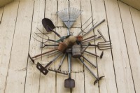 Vieux outils de ferme et de jardin accrochés au mur blanc de la grange dans le jardin de campagne de l'arrière-cour, Québec, Canada - août