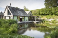 Maison au bord du lac conçue par Hugh Wray-McCann avec une terrasse en bois le long d'un côté à Am Brook Meadow dans le Devon.