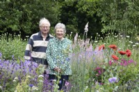 Couple debout dans leur prairie de fleurs sauvages à North Cottage, Whittington - Juillet