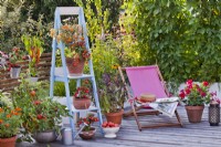 Toit-terrasse en terrasse avec légumes en pot, herbes et fleurs, transat et parterre de fleurs surélevé.
