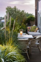 Au coucher du soleil, un écran feuillu sur un balcon abrite une salle à manger, créée à partir d'herbes ornementales, de laurier, de pittosporum, de néflier du Japon et d'oliviers.