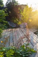 Terrasse en bois en bois avec deux chaises au coucher du soleil. RHS Garden pour un avenir vert. Conçu par Jamie Butterworth. RHS Hampton Court Palace Garden Festival Show, juillet 2021