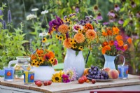 Présentoir de table avec bouquets de fleurs d'été avec dahlia, zinnia, rudbeckia, verveine et calendula dans des vases.