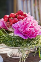 Présentoir à gâteaux avec couronne de fleurs sauvages, pivoines et fraises.