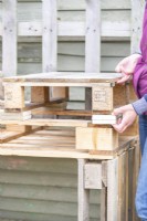 Femme plaçant des morceaux de bois sous des palettes plus petites pour faire de la place pour les tiroirs