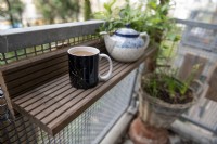 Étagère recyclée sur un balcon. Fabriqué à partir des balcons, les vieilles planches de terrasse en bois ont été remplacées. Tasse de thé au lait.