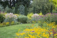 Parterre de jardin d'été conçu par Adrian Bloom, The Bressingham Gardens, Norfolk - AugustCortaderia selloana 'Patagonia', Eupatorium maculatum 'Gateway', Taxus baccata 'Fastigiata Robusta'.