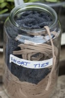 De vieux collants coupés en lanières font des liens pour le jardin. Les liens sont utilisés pour attacher les plantes grimpantes et sont stockés dans l'image dans un pot Mason.