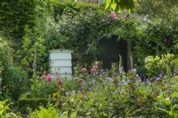 Jardin de ville isolé avec ruche entourée de Rosa 'Boscobel', de rosiers grimpants, de Géranium 'Brookside' et de digitales. Juin