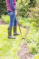 Femme utilisant des cisailles à bordure pour tailler le bord de la pelouse