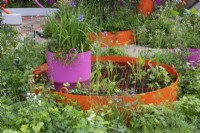 Dans une conception pour un parc urbain miniature, une jardinière ronde géante crée une pièce d'eau, un bac d'iris de Sibérie ajoutant de la hauteur.