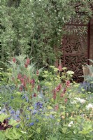 Jardin de style cottage romantique avec écran décoratif en forme de saule en métal.