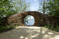 Passerelle faite de branches de saule près de la plage avec vue sur le lac réalisée par l'artiste naturaliste Will Beckers.