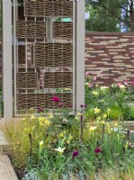 The Stitchers' Garden avec des jaunes doux et des roses profonds avec des murs en tapisserie et des paravents en saule.