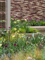 The Stitchers' Garden avec des jaunes doux et des roses profonds avec des murs en tapisserie et des paravents en saule.