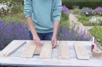 Femme utilisant un petit morceau de bois comme entretoise pour positionner uniformément les planches de bois coupées