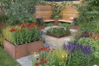 De simples bancs en bois donnent sur une pièce d'eau réfléchissante dans le jardin de la pause déjeuner au RHS Hampton Court Palace Garden Festival 2022
