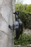 Une sculpture de pic faite à partir d'une vieille tête de bêche sur un arbre. Briar Cottage Jardin. Jardin Devon NGS. Le printemps