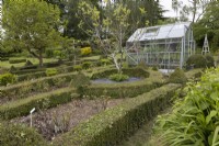 Une serre se trouve au milieu d'un jardin de nœuds. Lewis Cottage, jardin NGS Devon. Le printemps.
