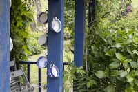 De vieilles tasses à thé sont réutilisées dans des décorations sur un hangar en bois bleu. Lewis Cottage, jardin NGS Devon. Le printemps.