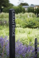 Marqueurs en bois avec les noms de femmes jardinières inspirantes dans une ferme florale en juillet