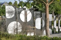 Deschampsia cespitosa 'Goldtau' devant des écrans en acier dans le Joy Club Garden au RHS Hampton Court Palace Garden Festival 2022