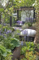 Pergola carbonisée au-dessus du coin salon dans le jardin des traces d'Abigail au RHS Malvern Spring Festival 2022