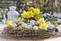 Décoration de table de Pâques avec nid d'oeufs en brindilles de saule, lichens et jonquilles.