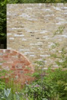 Les murs de briques nues contrastent avec les plantations douces et naturalistes. Été. Peut.