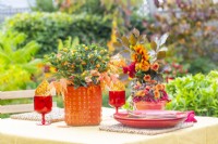 Présentoir de table automnal avec bol de chrysanthèmes, baies et pommettes avec un pot de brins de corne de cerf et Solanum 'Venus'