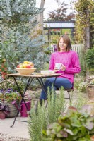 Femme assise à table dans un jardin avec une tasse de thé