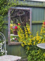 Réflexions de jardin dans un miroir encadré suspendu à une clôture de jardin