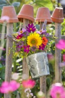 Bouquet de fleurs d'été contenant du tournesol, du cosmos, de la monarde, de la capucine, de l'agastache, du fenouil et du dahlia suspendu à une clôture.