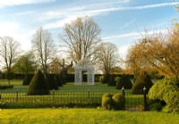 Un belvédère en fer blanc entouré de pyramides de Taxus baccata sur la pelouse du Parterre à Chenies Manor.