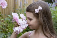 Jeune fille sentant des roses dans le jardin arrière