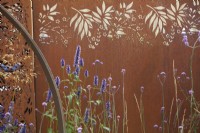 Parterre de fleurs d'été avec agastache, verveine et graminées ornementales devant un séparateur en acier Corten. Juillet. Spectacles floraux.