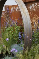Élément de jardin en acier Corten et panneaux de fond avec plantation colorée mixte. Le jardin du soleil. Conception : Charlie Bloom et Simon Webster. RHS Hampton Court Garden Festival 2022.