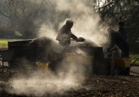 Vapeur s'élevant d'un tas de compost et de jardiniers le pelletant sur le sol à Kew Gardens, Londres.