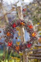 Couronne faite de baies de lierre de Boston, de lichens et de feuillage d'érable d'automne sur poteau en bois.