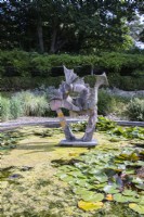 Sculpture de dragon dans un étang avec des algues et des nénuphars.août. Été