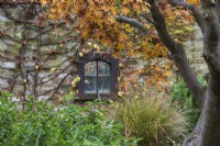 Un miroir encadré reflète des images du feuillage d'automne doré sur un acer japonais.