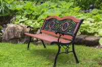 Meubles anciens en bois peint orange brunâtre et banc en fonte noire dans le jardin de la cour avant au printemps