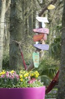 Pot rempli de tulipes et de jonquilles et de plaques signalétiques colorées sur la branche.