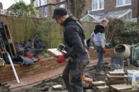 Un ouvrier portant une dalle de York Stone utilisée pour construire une terrasse lors de la rénovation d'un jardin londonien.