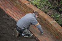 Un travailleur pointant les briques sur un chemin nouvellement construit lors de la rénovation d'un jardin de Londres.