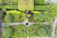 Vue sur jardin rectangulaire avec allées cruciformes en gravier avec de grands monticules d'Osmanthus burkwoodii et des haies de Buis. Juillet. Été. Image prise depuis un drone.