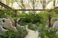 Des panneaux de béton et une grille métallique encadrent un sentier à travers les plantes vivaces dans les Samaritains' Listening Garden a Show Garden conçu par Darren Hawkes au RHS Chelsea Flower Show 2023